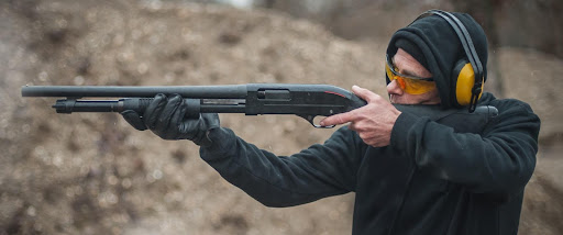 Man aiming pump shotgun for shooting training.